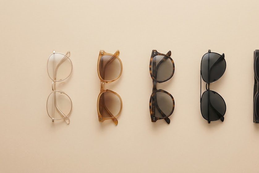 Cinq paires de solaires alignées sur un fond beige, des teintes les plus claires aux plus sombres