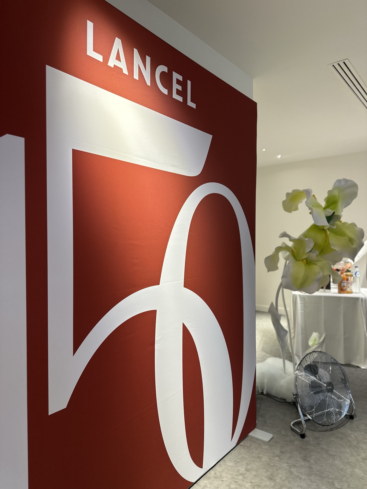 Le panneau Lancel rouge à l'entrée du showroom, le monogramme de la marque en blanc