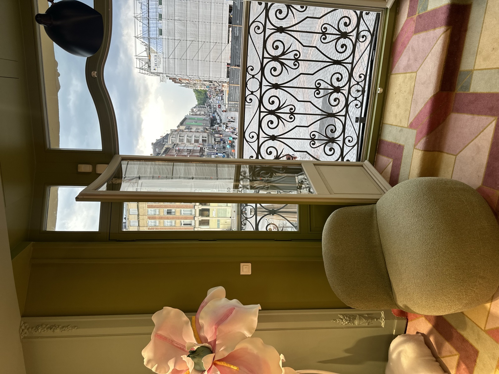 Le showroom Lancel : un fauteuil devant une porte-fenêtre ouverte sur un balcon, une grande fleur en papier posée à côté