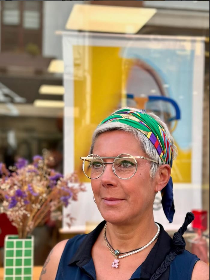 Cliente portant des lunettes de vue rondes dorées devant la boutique, Gravelines Optique à Montivilliers