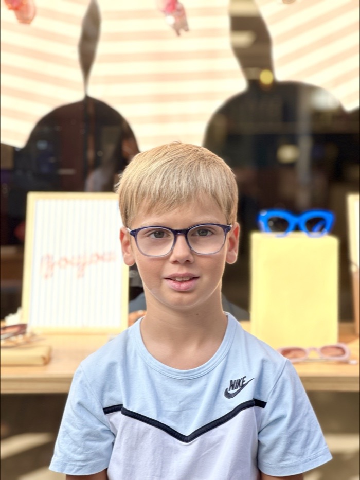 Jeune garçon portant des lunettes de vue bleues devant la vitrine, Gravelines Optique à Montivilliers