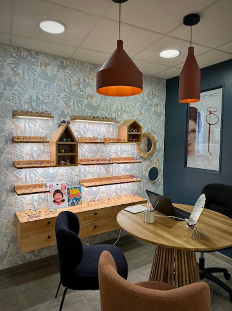 Espace enfant de la boutique Gravelines Optique à Montivilliers : étagères de montures enfant, papier peint jungle et table dédiée