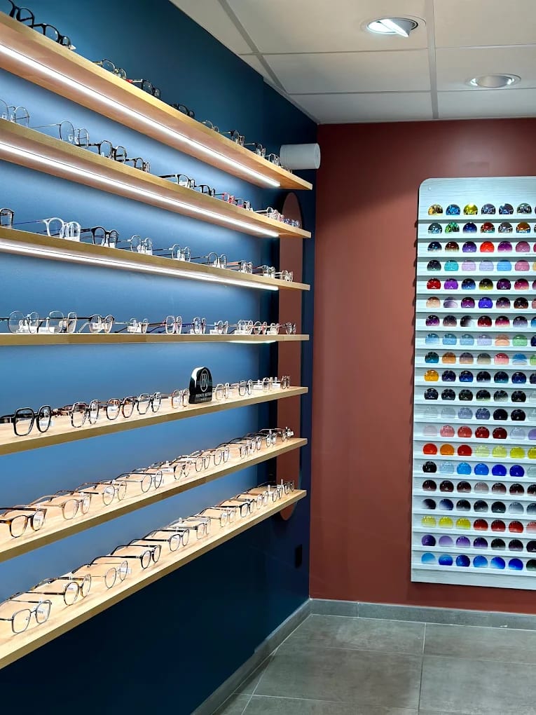 Mur de montures sur étagères éclairées et présentoir de teintes de verres, en boutique chez Gravelines Optique à Montivilliers