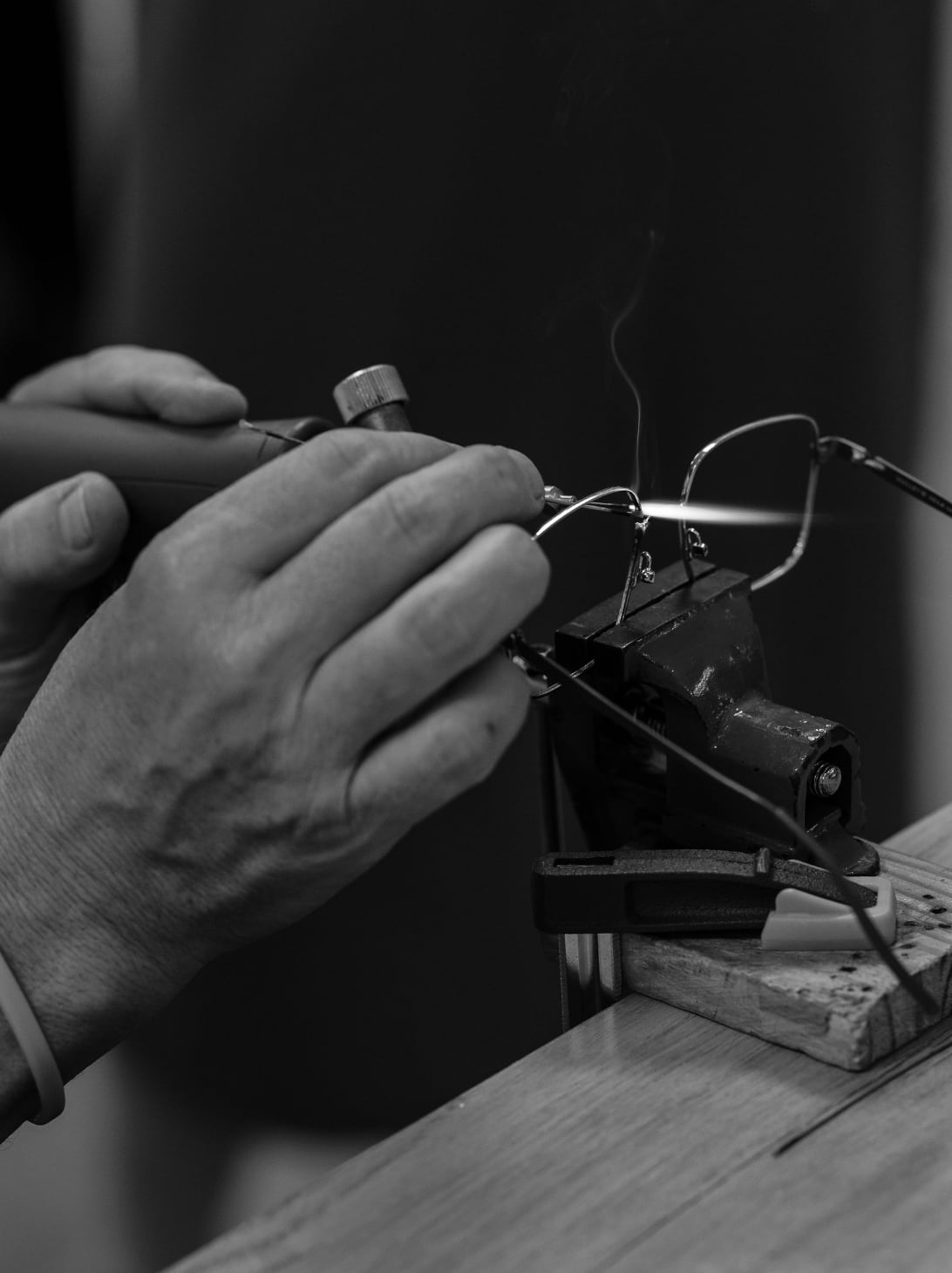 Soudure d'une branche métal au chalumeau, à l'atelier de Gravelines Optique : la monture tenue dans un étau, la flamme au point de soudure